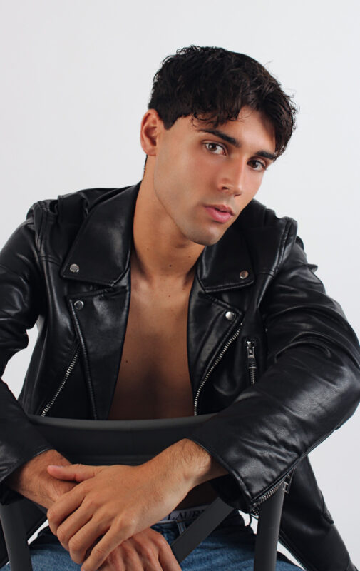 Modelo chico con pelo oscuro y ojos marrones con chaqueta de cuero